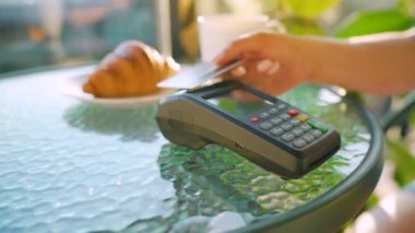 NFC kredi kartı ödemesi. NFC teknolojisiyle bağlantısız kredi kartıyla ödeme yapan bir kadın bir kafedeki banka terminalinden sipariş veriyor. Kablosuz para transferi. Kablosuz ödeme