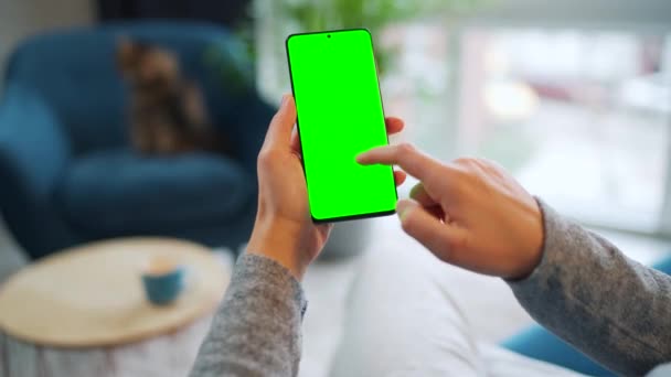 Žena doma pomocí chytrého telefonu se zelenou maketou obrazovky ve vertikálním režimu. Dívka procházející internet, sledující obsah, videa. POV. — Stock video