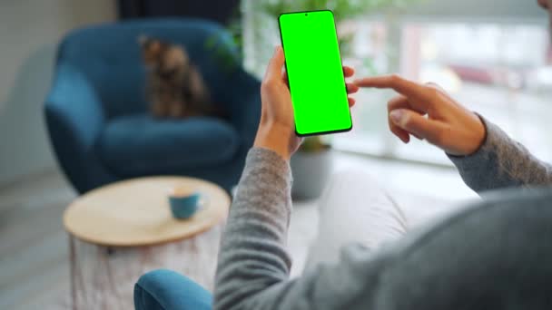 Mujer en casa usando smartphone con pantalla verde en modo vertical. Chica navegando por Internet, viendo contenido, videos. POV. — Vídeo de stock