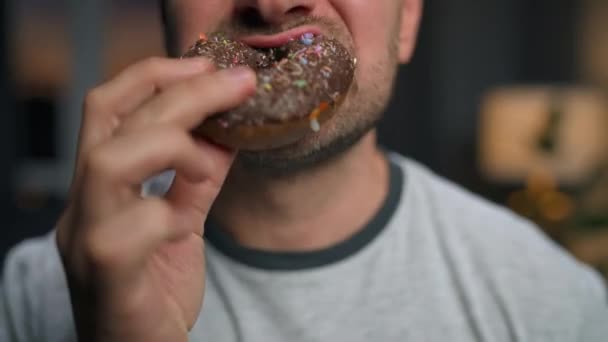 De man eet haastig zoete chocolade donut. Close-up — Stockvideo