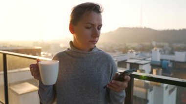 Kadın güne bir fincan çay ya da kahveyle başlıyor ve şafak vakti balkondaki akıllı telefonundaki e-postaları kontrol ediyor..