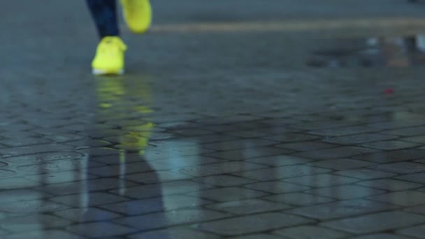 女性のスポーツ女性の屋外では、水たまりに足を踏み入れるジョギング。雨の中を走る単一走者は、スプラッシュを作る。スローモーション — ストック動画