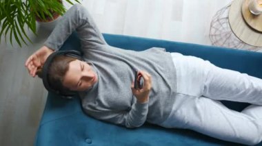 Kablosuz kulaklık takan, müzik dinleyen, mobil uygulama kullanan ya da sosyal ağlarda akıllı telefondan iletişim kuran bir kadın. Kamera saat yönünde döner