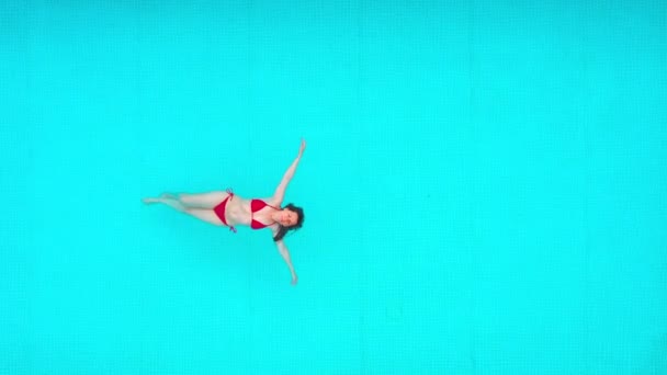 Vue du haut comme une femme en maillot de bain rouge couchée sur le dos dans la piscine. Concept relaxant — Video