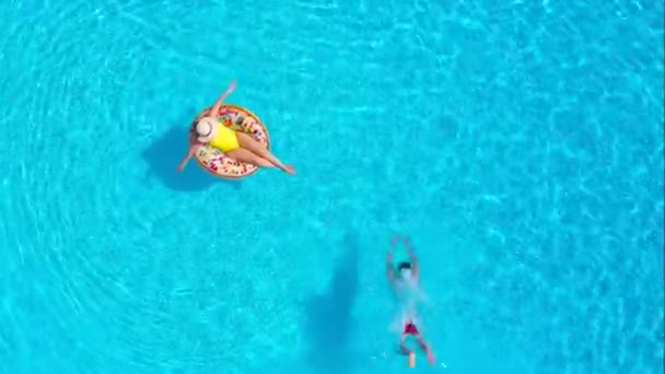 Luftfoto af mand dykker ned i poolen, mens pigen ligger på en donut pool flyde – Stock-video