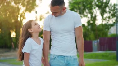 Baba ve kızı gün batımında kendi bölgelerinde dolaşırlar. Çocuk babasının elini tutuyor. Yavaş çekim