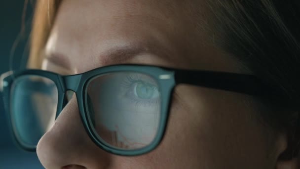 Γυναίκα με γυαλιά που κοιτάζει στην οθόνη και δουλεύει με διαγράμματα και αναλύσεις. Η οθόνη της οθόνης αντανακλάται στα γυαλιά. Δουλειά τη νύχτα. Πολύ κοντινό πλάνο. — Αρχείο Βίντεο