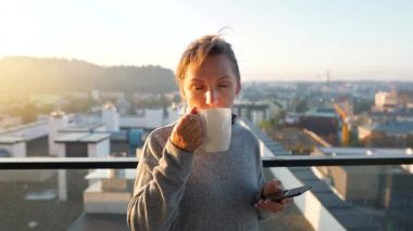 Kadın güne bir fincan çay ya da kahveyle başlıyor ve şafak vakti balkondaki akıllı telefonundaki e-postaları kontrol ediyor..