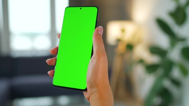 Femme à la maison à l'aide d'un smartphone avec écran vert maquette en mode vertical. Fille naviguant sur Internet, regarder du contenu, des vidéos. Point de vue. — Video