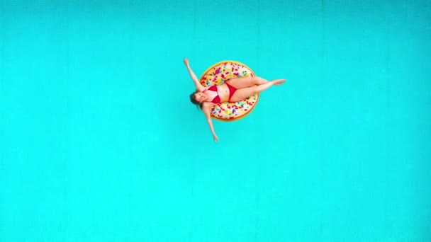 Vista aérea de una mujer en bikini rojo nadando en una dona en la piscina — Vídeos de Stock