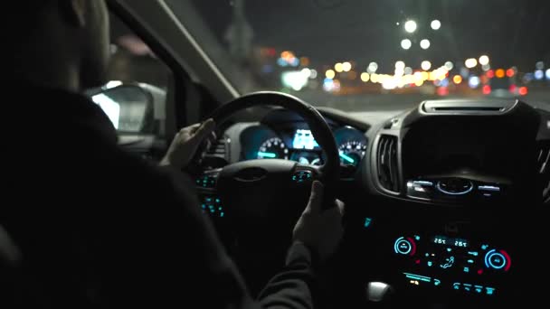 Gece şehrinin sokaklarında araba süren bir adam. Arabanın arka koltuğundan bak.. — Stok video