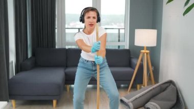 Kulaklıklı bir kadın evi temizliyor ve konserdeki bir yıldız gibi süpürgeyle şarkı söyleyerek eğleniyor. Yavaş çekim