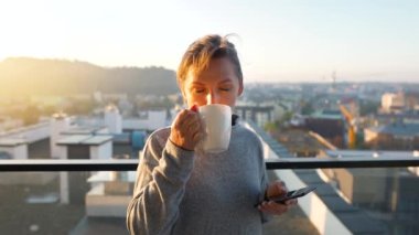 Kadın güne bir fincan çay ya da kahveyle başlıyor ve şafak vakti balkondaki akıllı telefonundaki e-postaları kontrol ediyor..