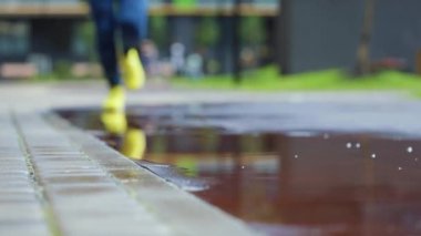 Bayan sporcu kadın dışarıda koşuyor, su birikintisine giriyor. Yağmurda koşan tek koşucu, su sıçratıyor. Yavaş çekim