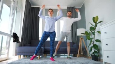 Kafkasyalı çift evde kardiyo egzersizi yapıyor. Rahat, aydınlık bir odada, ağır çekimde..