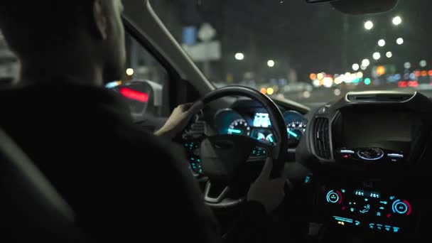 Mannen som kör bil genom gatorna i nattstaden. Utsikt från bilens baksäte. — Stockvideo