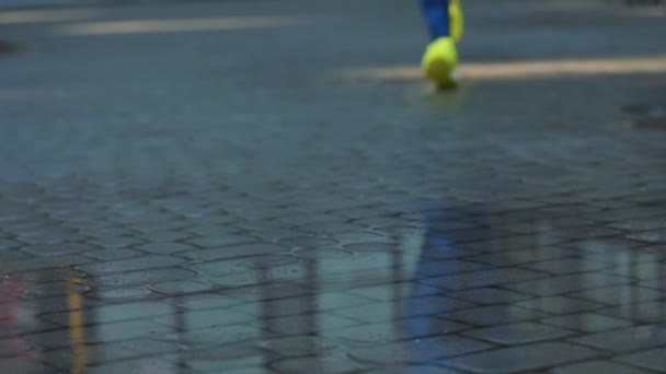 Mulher esportiva correndo ao ar livre, entrando em poça. Um corredor a correr à chuva, a fazer salpicos. Movimento lento — Vídeo de Stock