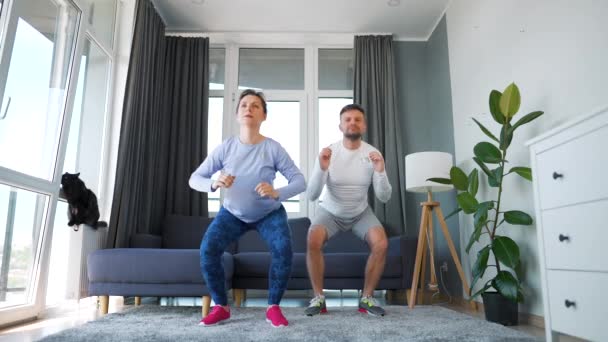 Caucásico pareja está haciendo ejercicio cardiovascular en casa en acogedora habitación luminosa, cámara lenta. — Vídeo de stock