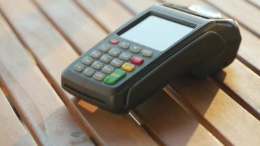 Akıllı telefondan yapılan temassız ödeme. Kablosuz ödeme konsepti. Yakın plan, kadın banka terminalindeki siparişi ödemek için akıllı telefon nakitsiz cüzdan teknolojisi kullanıyor..