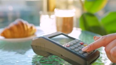Akıllı telefondan yapılan temassız ödeme. Kablosuz ödeme konsepti. Yakın plan, kadın bir kafedeki banka terminalinin siparişini ödemek için akıllı telefon nakitsiz cüzdan teknolojisi kullanıyor..