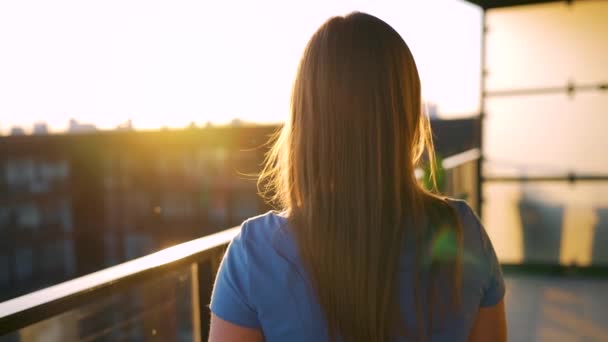 Mulher com uma xícara de café em pé na varanda e admirar o pôr do sol. Movimento lento — Vídeo de Stock