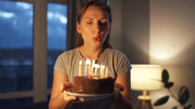 Mutlu, heyecanlı bir kadın Noel pastasına mum üflüyor, doğum gününü evde kutluyor, ağır çekimde.