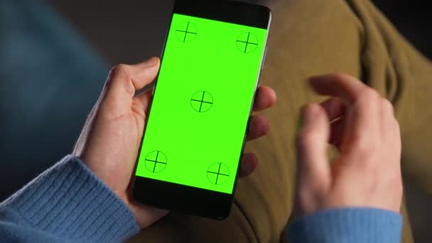 Man använder smartphone med grön mock-up skärm i vertikalt läge. Man surfar på Internet, tittar på innehåll, videor. — Stockvideo