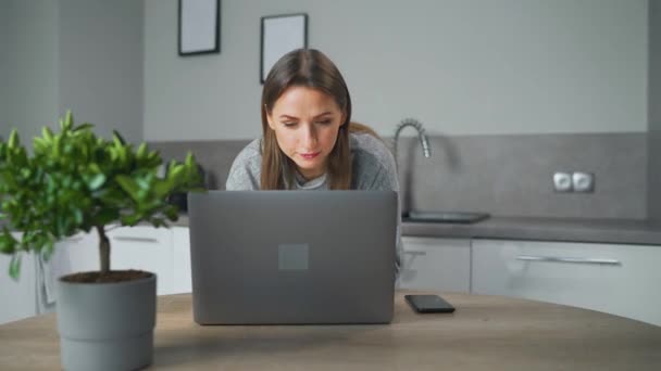Nő áll otthon konyha használata laptop szabadúszó munka keres fókuszált mélyen elveszett gondolatok, gondolkodás problémák megoldása távolról teszi a kutatást. — Stock videók