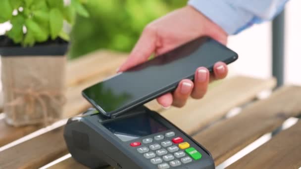 Contactless payment with smartphone. Wireless payment concept. Close-up, woman using smartphone cashless wallet NFC technology to pay order on bank terminal. — Stock Video