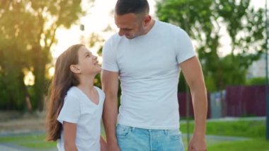 Baba ve kızı gün batımında kendi bölgelerinde dolaşırlar. Çocuk babasının elini tutuyor. Yavaş çekim