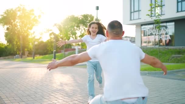 Kızı babasına koşuyor ve ona sarılıyor. Baba çocuğu kollarına alır. Yavaş çekim — Stok video
