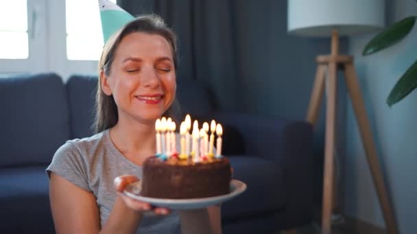 Felice donna eccitata rendendo caro desiderio e soffiando candele sulla torta di festa, festeggiando il compleanno a casa — Video Stock