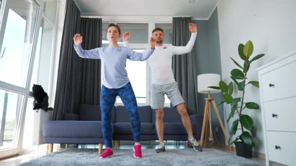 Caucasian couple is doing cardio exercise at home in cozy bright room, slow motion. — Stock Video