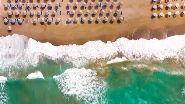 Widok z powietrza na morze, piaszczysta plaża, parasole i leżaki, nierozpoznane ludzi.Piękne miejsce wypoczynku i turystyki na Krecie, Grecja. — Wideo stockowe