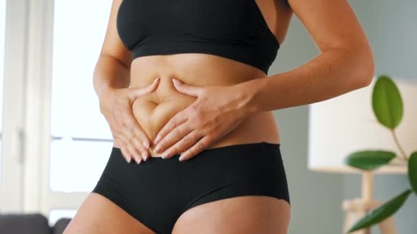 Frau, die die Haut auf ihrem Bauch zusammenpresst und auf Cellulite und überschüssiges subkutanes Fett überprüft — Stockvideo