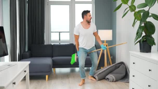 Uomo che pulisce la casa e si diverte a ballare con una scopa. — Video Stock