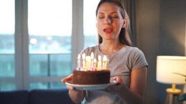 Mutlu, heyecanlı bir kadın Noel pastasına mum üflüyor, doğum gününü evde kutluyor, ağır çekimde.