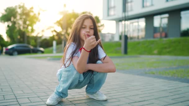 Retrato de chica positiva con el pelo largo mirando a la cámara una puesta de sol. Movimiento lento — Vídeos de Stock