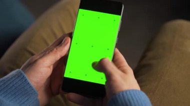 Adam dikey modda yeşil ekran ile akıllı telefon kullanıyor. İnternette gezinen, içeriği izleyen, videolar.