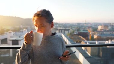 Kadın güne bir fincan çay ya da kahveyle başlıyor ve şafak vakti balkondaki akıllı telefonundaki e-postaları kontrol ediyor..
