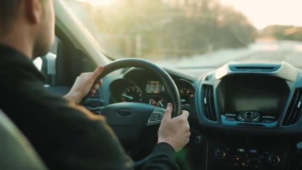 Mann fährt Auto auf der Straße, die untergehende Sonne scheint in die Windschutzscheibe — Stockvideo