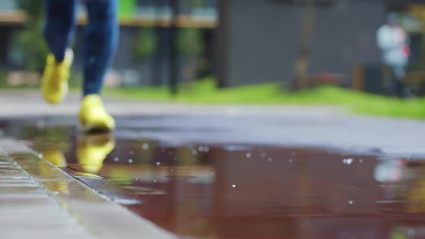 Femme sportive faisant du jogging à l'extérieur, entrant dans la flaque d'eau. Un seul coureur court sous la pluie, faisant des éclaboussures. Mouvement lent — Video