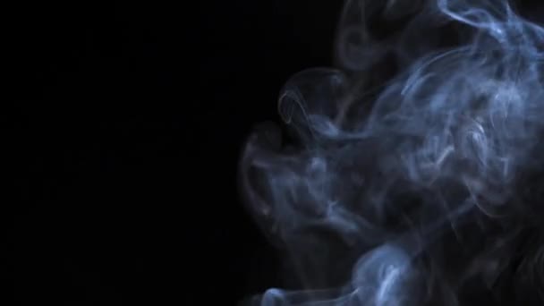 Humo abstracto se levanta en hermosos remolinos sobre un fondo negro — Vídeos de Stock