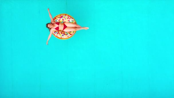 Vista aérea de uma mulher de biquíni vermelho nadando em um donut na piscina — Vídeo de Stock