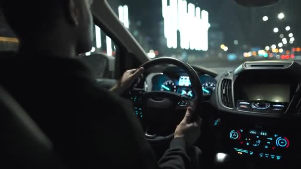 밤에 도시의 거리를 운전하는 남자. 차의 뒷좌석에서 바라본 광경. — 비디오