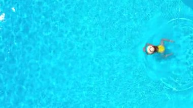 Sarı mayo giymiş bir kadının havuzda yüzüşünü yukarıdan izleyin. Yaz yaşam tarzı