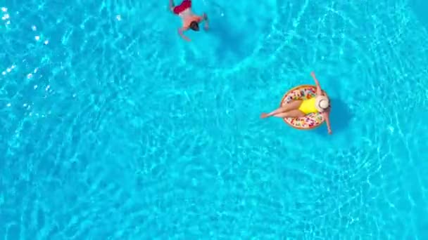Draufsicht eines Paares, das sich im Pool vergnügt, der Mann schwimmt und die Frau liegt auf einem aufblasbaren Donut — Stockvideo