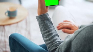 Evde dikey modda yeşil ekranlı akıllı telefon kullanan bir kadın var. Kız internette geziniyor, içeriği izliyor, videolar