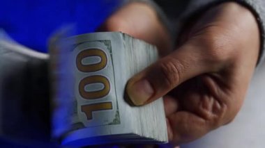 Amerikan Doları faturalarını sayan ya da arka plandaki polis arabalarının ışıklarına karşı nakit ödeme yapan eller.