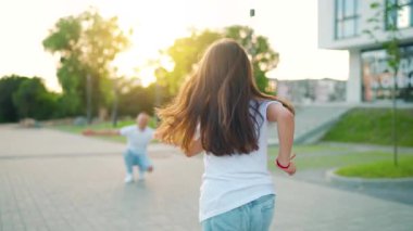 Kızı babasına koşuyor ve ona sarılıyor. Baba çocuğu kollarına alır. Yavaş çekim